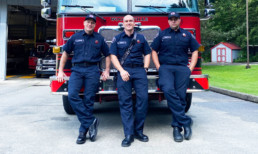 Three Woodinville fire fighters in front of fire engine